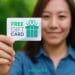 Woman holding a card labeled “Free Gift Card” with the DollarSprout logo visible, symbolizing how to earn free gift cards through everyday actions