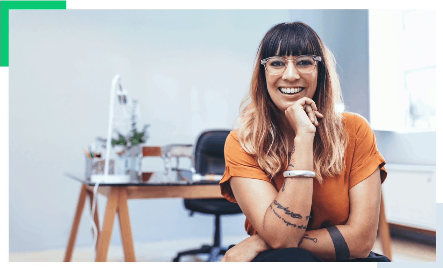 young woman sitting at a desk smiling into camera