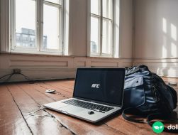 A laptop sitting on a bare wooden living room floor, representing the risk that entrepreneurs take when venturing out on their own.