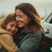 woman hugging child in front of recently received free car
