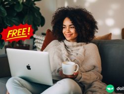 A woman holding a cup of coffee and looking at her laptop. There is a 