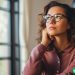 A woman wearing glasses and looking up and away, wondering how many bank accounts she should have.