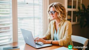A blonde woman in her early forties who is writing an article on her laptop.