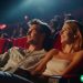 A young couple sitting in a movie theater and looking at the screen.