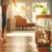 A dramatic shot of a large jar with coins, with a woman walking past it. The jar represents the idea of saving money.