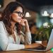 A well dressed female wearing glasses, working on her laptop. She is trying to find clients online.