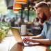 A man sitting at an outdoor cafe working on his Wordpress website.