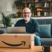 A man in his early 50s sitting with his laptop and an Amazon package.