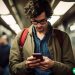 A man in his 30s on the subway looking at his phone as he scrolls through X (formerly known as Twitter)