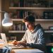 A college freshman male doing some online work on his laptop in his dorm room.