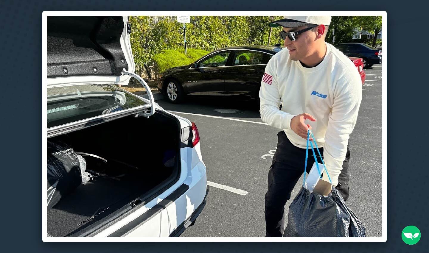 Martin De Anda loading delivery bags into the trunk of his car while wearing Airtasker gear