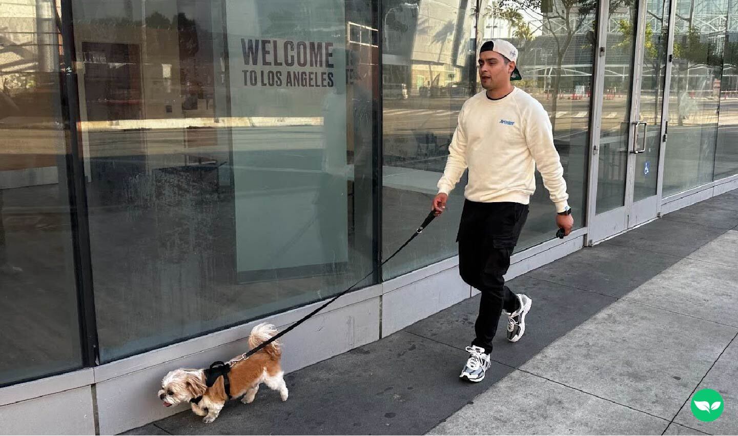 Martin De Anda walking a small dog along a city sidewalk in Los Angeles