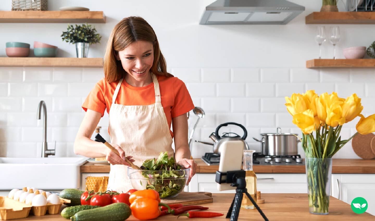 Woman recording a cooking video in her kitchen, representing content creation on YouTube.