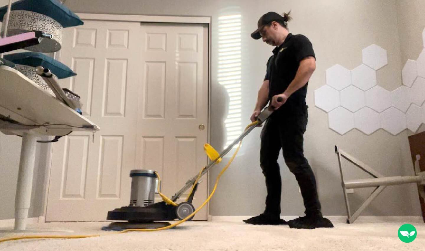 Kyle Stroud cleaning a carpeted room using a rotary floor machine.