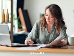 Woman working at a laptop with paperwork and coffee, representing the middle-class creator economy.